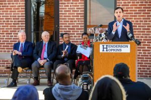 JHU President Ron Daniels speaking at a podium that says "Henderson Hopkins" on it.