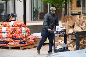 A person pushing a cart of groceries outside.